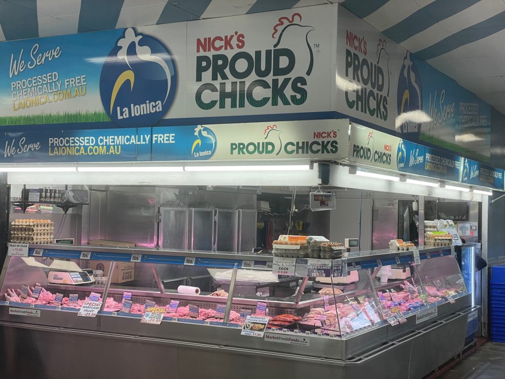 Butcher Counter with Fresh Chicken and Eggs Raw chicken pieces and eggs displayed in a refrigerated butcher counter with "Nick's Proud Chicks" signage.